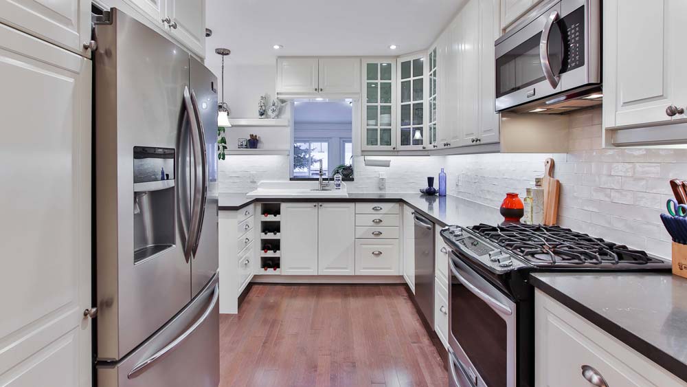 A kitchen with stainless steel appliances: a fridge, a microwave, an oven and a dishwasher.