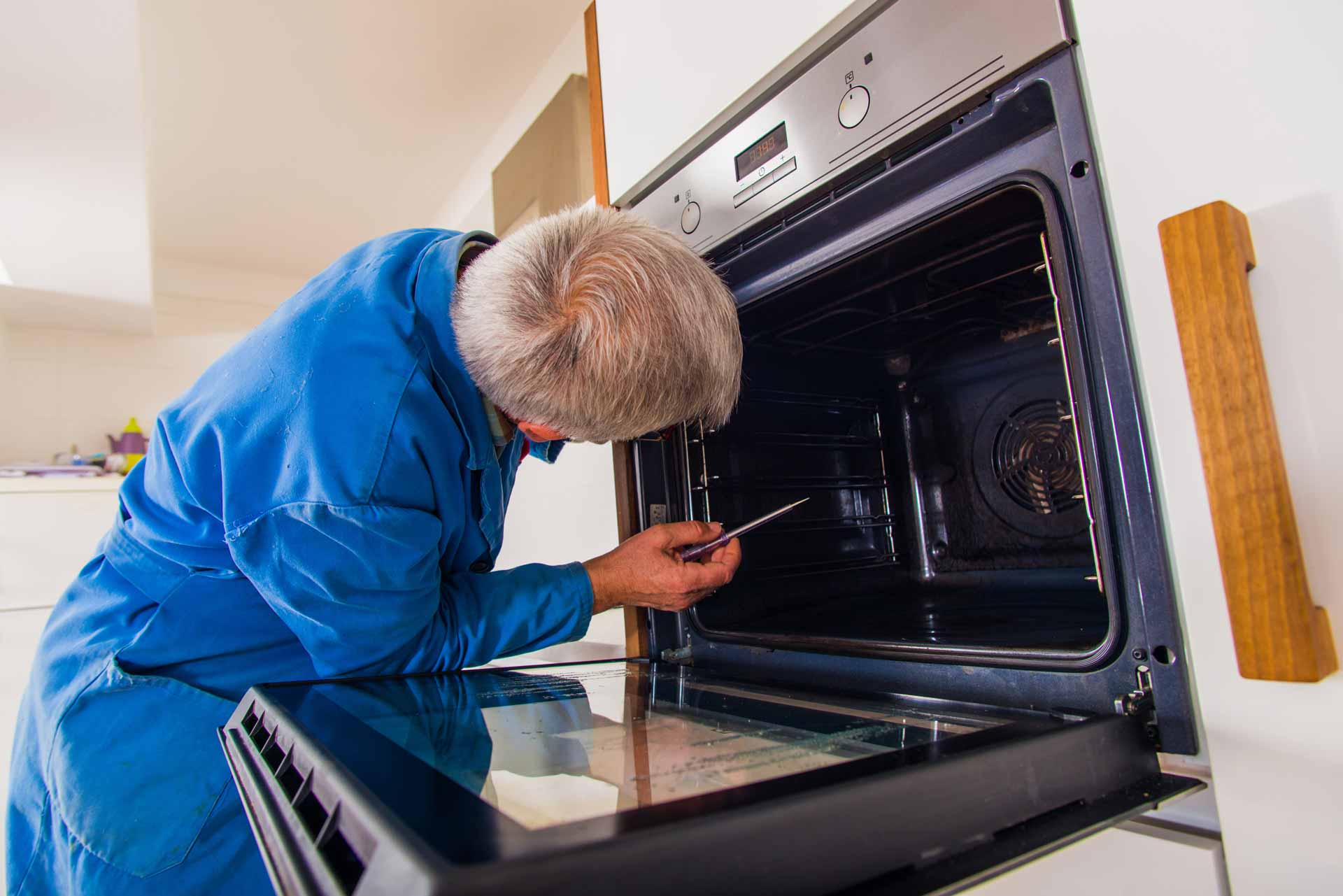 Appliance repair technician working on a wall oven