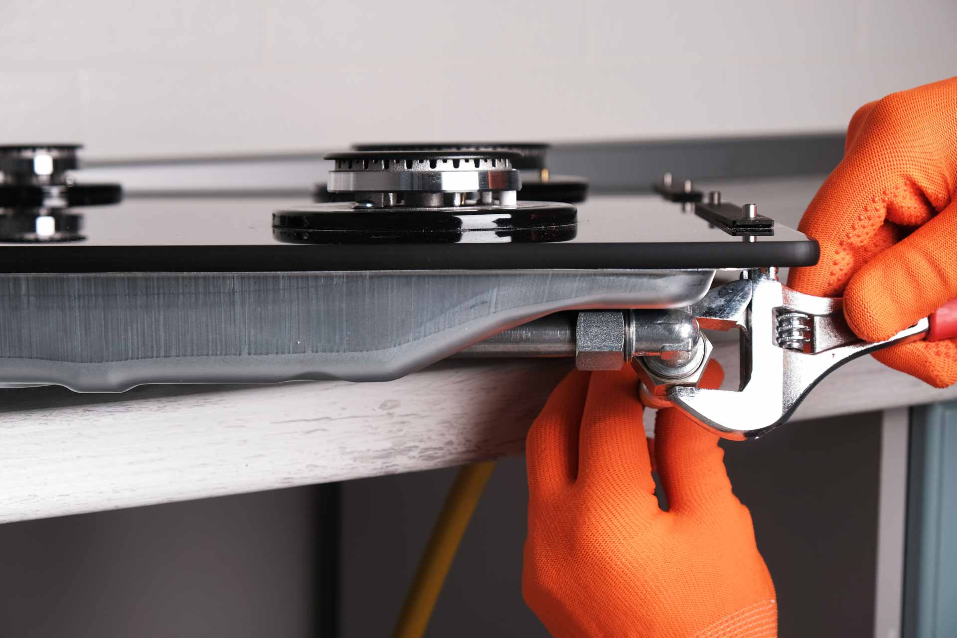 Technician wearing orange gloves repairing a gas stove